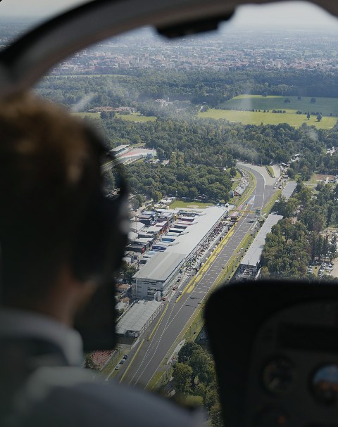 View over the pilot's shoulder from the cockpit, looking down on countryside and a road