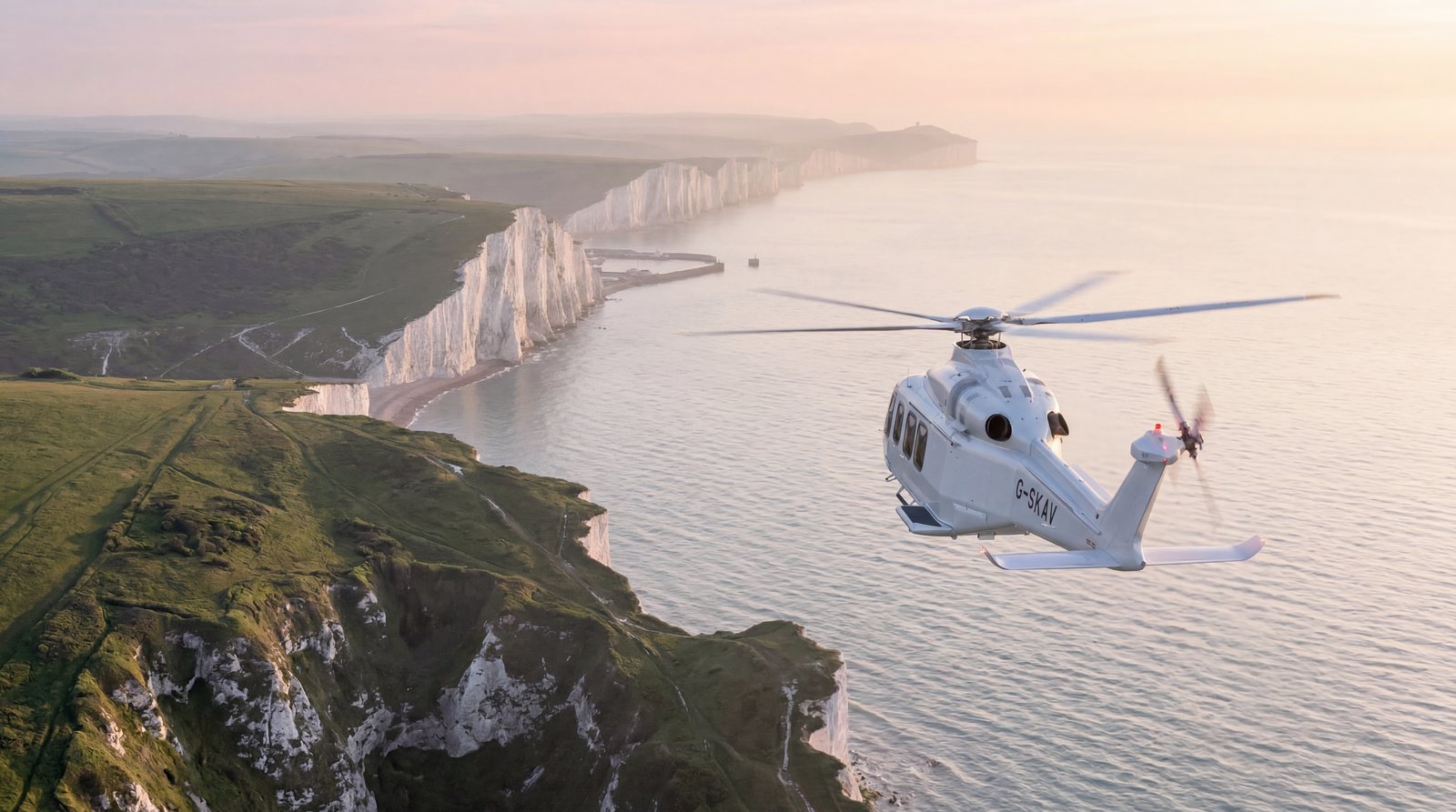 Helicopter flying along white chalk cliffs above the sea